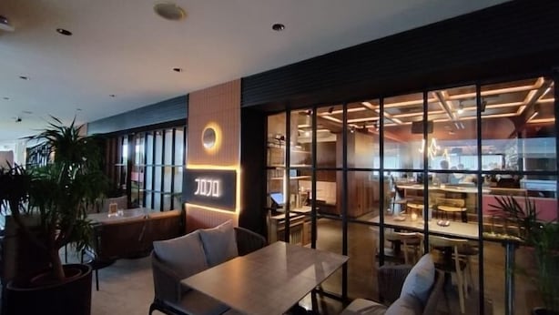 A modern restaurant with a glass partition, wooden furniture, and a neon sign. - reStary Cartoon Themed Homestay (Kota Kinabalu)