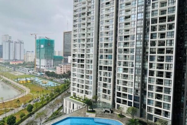 A high-rise building with multiple floors, a swimming pool, and a view of a construction site in the background.