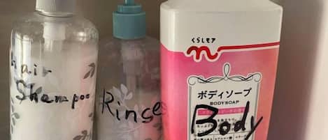 Drie flessen vloeistof, waarvan er één roze is en Japanse tekst heeft.