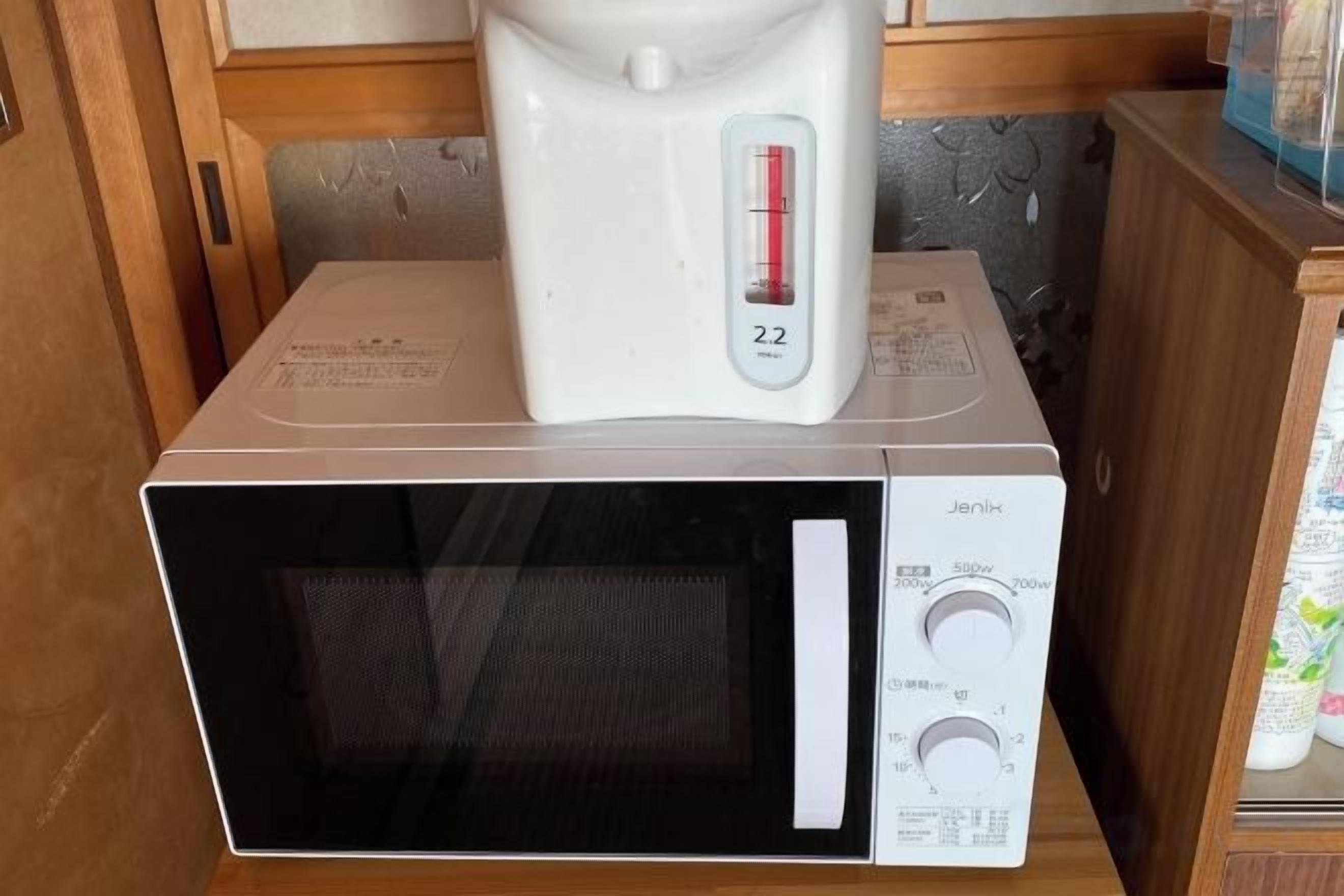 A microwave oven with a digital display and a coffee maker on top.