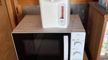 A microwave oven with a digital display and a coffee maker on top.