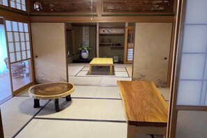 A traditional Japanese room with tatami flooring, a low wooden table, a round wooden table, and a sliding door. - Kushimoto, Minpaqu "Azashi" (Kushimoto)