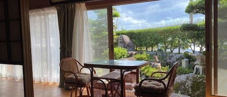 A traditional Japanese room with tatami flooring, a low table, and four cushioned chairs.