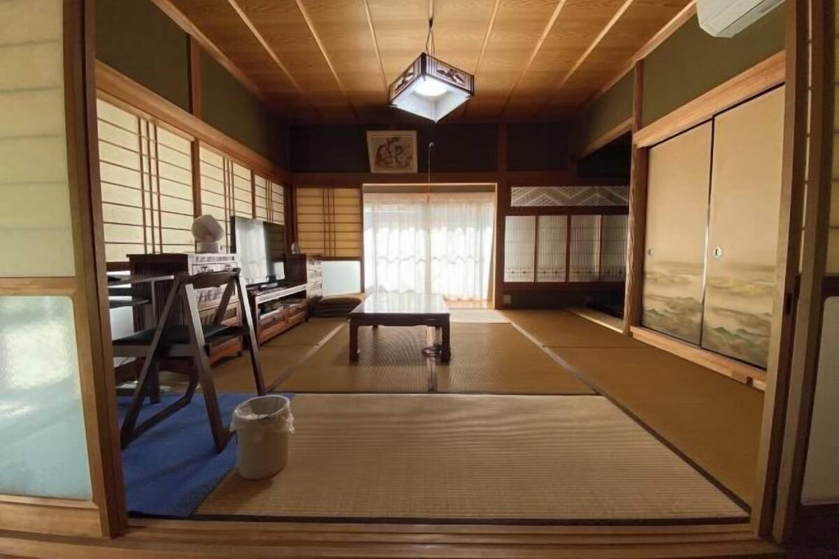 A traditional Japanese room with tatami flooring, sliding doors, and a low wooden ceiling.