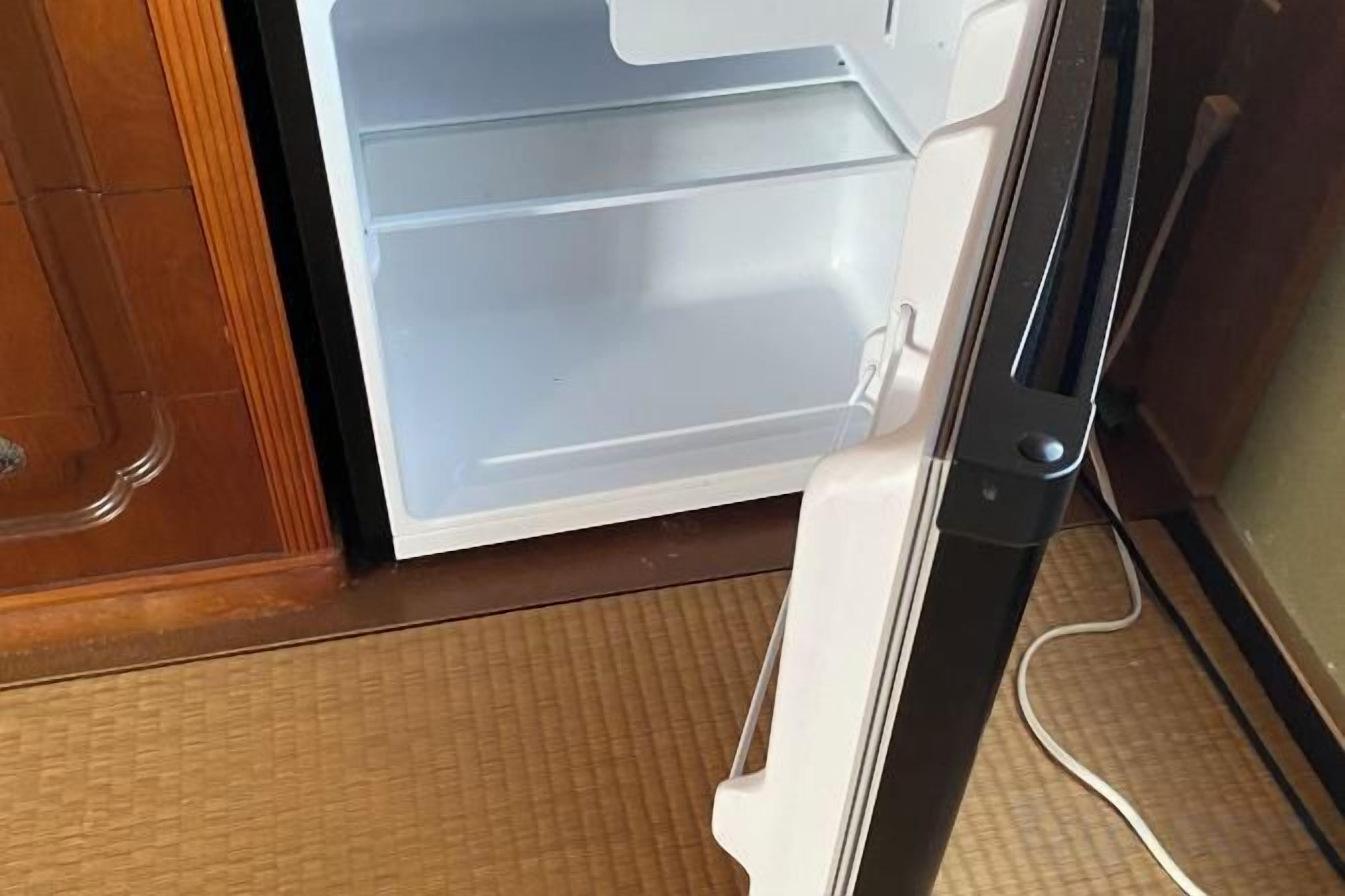 A white refrigerator with a freezer compartment, a handle, and a control panel.
