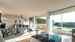 A modern living room with a large glass door leading to an outdoor patio.