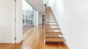 A modern staircase with wooden steps and glass doors leading to a balcony.