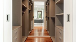 A walk-in closet with wooden flooring and grey shelving units.