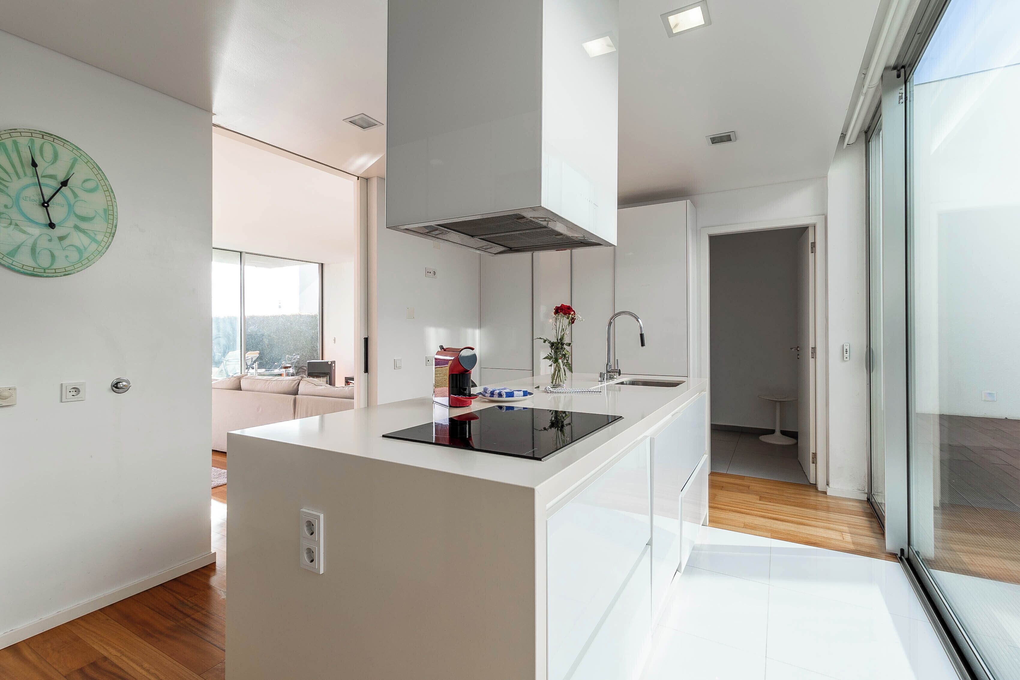 A modern kitchen with a central island, a built-in stove, and a large window.