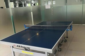 A ping pong table with a white base and wheels, labeled 'DOUBLE FISH,' in a room with glass partitions and a tiled floor. - The Wellington Homes - Botanica Premier Apartment - Nearby Airport Free Pool Gym (Ho Chi Minh City)
