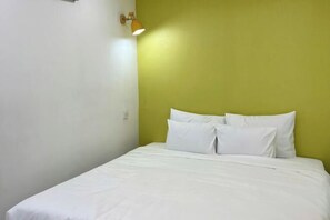 A single-bed room with white bedding, a green accent wall, and a wall-mounted lamp. - The Wellington Homes - Botanica Premier Apartment - Nearby Airport Free Pool Gym (Ho Chi Minh City)