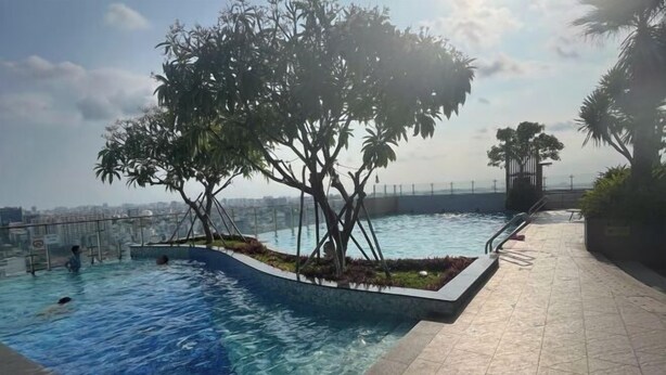 A swimming pool with a tree in the center, surrounded by a tiled deck. - The Wellington Homes - Botanica Premier Apartment - Nearby Airport Free Pool Gym (Ho Chi Minh City)