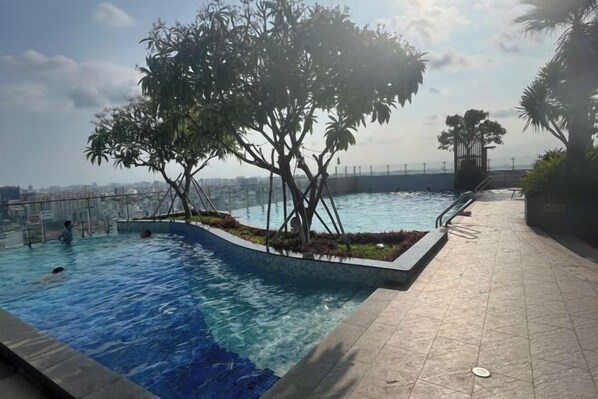 A swimming pool with a tree in the center, surrounded by a tiled deck. - The Wellington Homes - Botanica Premier Apartment - Nearby Airport Free Pool Gym (Ho Chi Minh City)