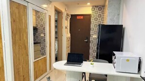 A compact kitchen with a white countertop, a laptop, a refrigerator, and a door with a sign. - The Wellington Homes - Botanica Premier Apartment - Nearby Airport Free Pool Gym (Ho Chi Minh City)