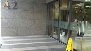 A hotel entrance with a large 'A2' sign, a glass door, and a yellow caution sign on the floor. - The Wellington Homes - Botanica Premier Apartment - Nearby Airport Free Pool Gym (Ho Chi Minh City)