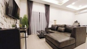 Ein modernes Wohnzimmer mit einer Couch, einem Couchtisch und einem an der Wand befestigten Fernseher.