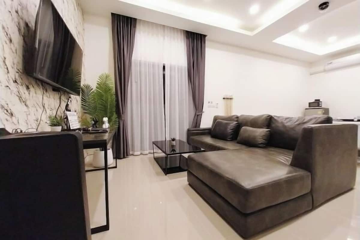 A modern living room with a sofa, a coffee table, and a TV mounted on the wall.