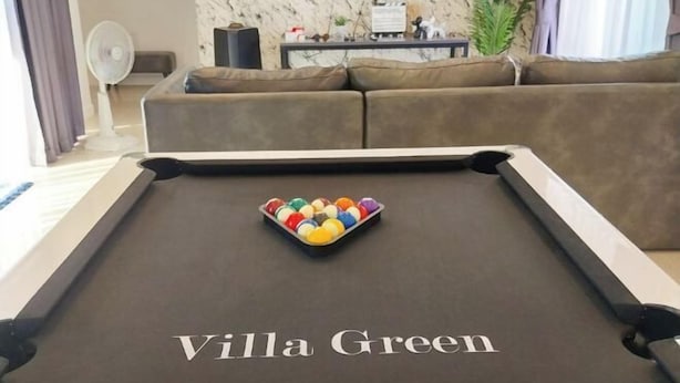 A pool table with the text "Villa Green" on the surface, a brown sofa, a fan, and a plant in the background. - 3 Bedroom Villa Green Mellow-Pattaya (Bang Lamung)
