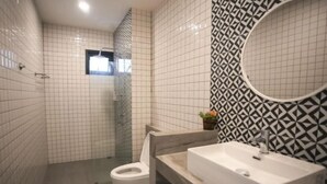 A modern bathroom with white tiled walls, a glass shower enclosure, a white toilet, and a vanity with a sink and mirror. - 3 Bedroom Villa Green Mellow-Pattaya (Bang Lamung)