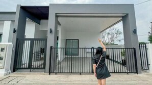 A modern building with a covered entrance and a gated driveway. - 3 Bedroom Villa Green Mellow-Pattaya (Bang Lamung)
