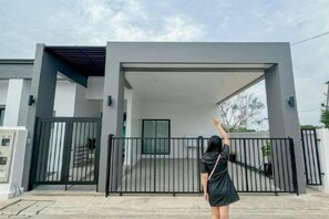 Un edificio moderno con acceso cubierto, un camino de entrada con portón y cielo despejado.