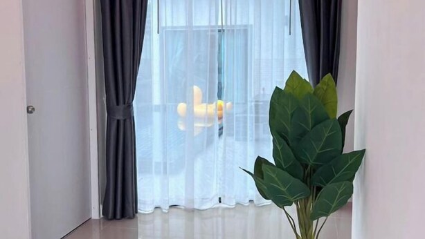 A room with a large window, a plant, and a door. - 3 Bedroom Villa Green Mellow-Pattaya (Bang Lamung)