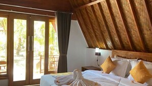A hotel room with a bed, pillows, a nightstand, and a view through a sliding door. - Wani Bali Resort 2 (Bali)