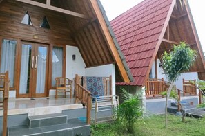 A wooden house with a red roof, a porch with chairs, and a small garden. - Wani Bali Resort 2 (Bali)