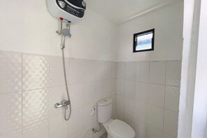 Een badkamer met witte betegelde wanden, een toilet, een douche met handdouche en een raam.