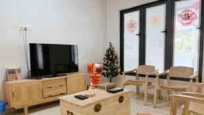 A living room with a TV, wooden furniture, a Christmas tree, and a sliding glass door. - leisurecorner 25 (Bukit Mertajam)