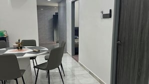 Un coin repas moderne avec une table ronde, quatre chaises et un vase contenant des ustensiles.