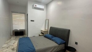 Une chambre à coucher comprenant un lit, une table de chevet, une chaise, un miroir et un appareil de climatisation.
