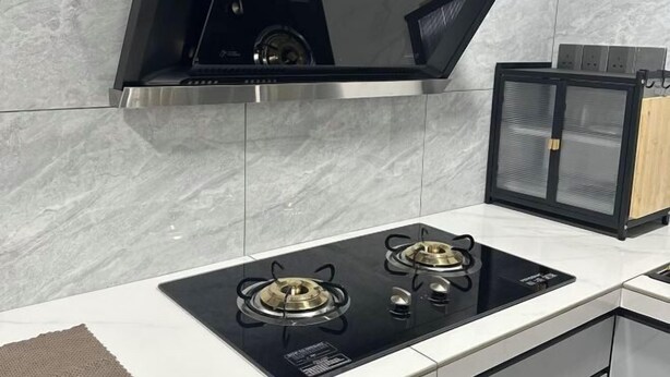 Une cuisine moderne dotée d’une plaque de cuisson à induction noire et d’une hotte en acier inoxydable.
