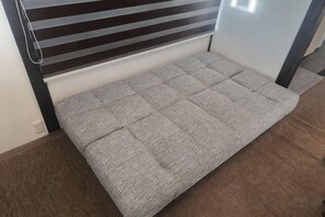 Una cama con cabecera y una ventana con persianas.