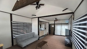 A living room with a sofa, a coffee table, and a ceiling fan. There is a kitchen visible through an open doorway. - [Panoramic view of the sea!] 28 minutes by car to Kinosaki Onsen (Kyotango)