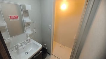 A bathroom with a sink, mirror, and a shower area.