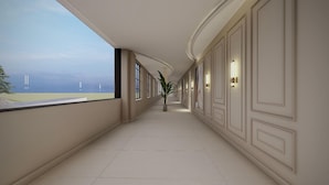 A corridor with a view of the sea, a potted plant, and wall-mounted lights. - Myrica Groves Lansdowne (Lansdowne)
