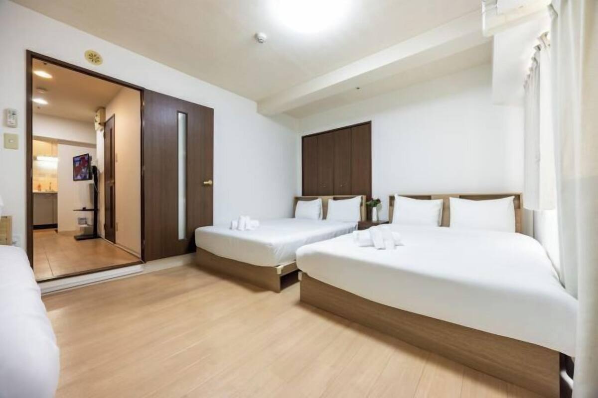 Ein Hotelzimmer mit zwei Einzelbetten, einem großen Bett, einem Kleiderschrank und einem Spiegel.