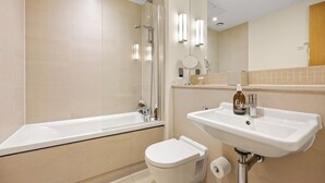 A modern bathroom with a bathtub, toilet, sink, and mirror. - Kula London Kensington (London)