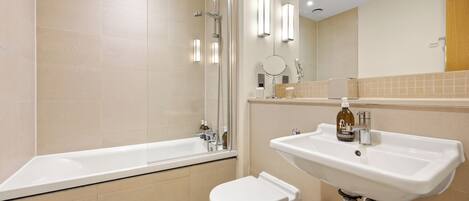 Un baño moderno con bañera, inodoro, lavabo y espejo.
