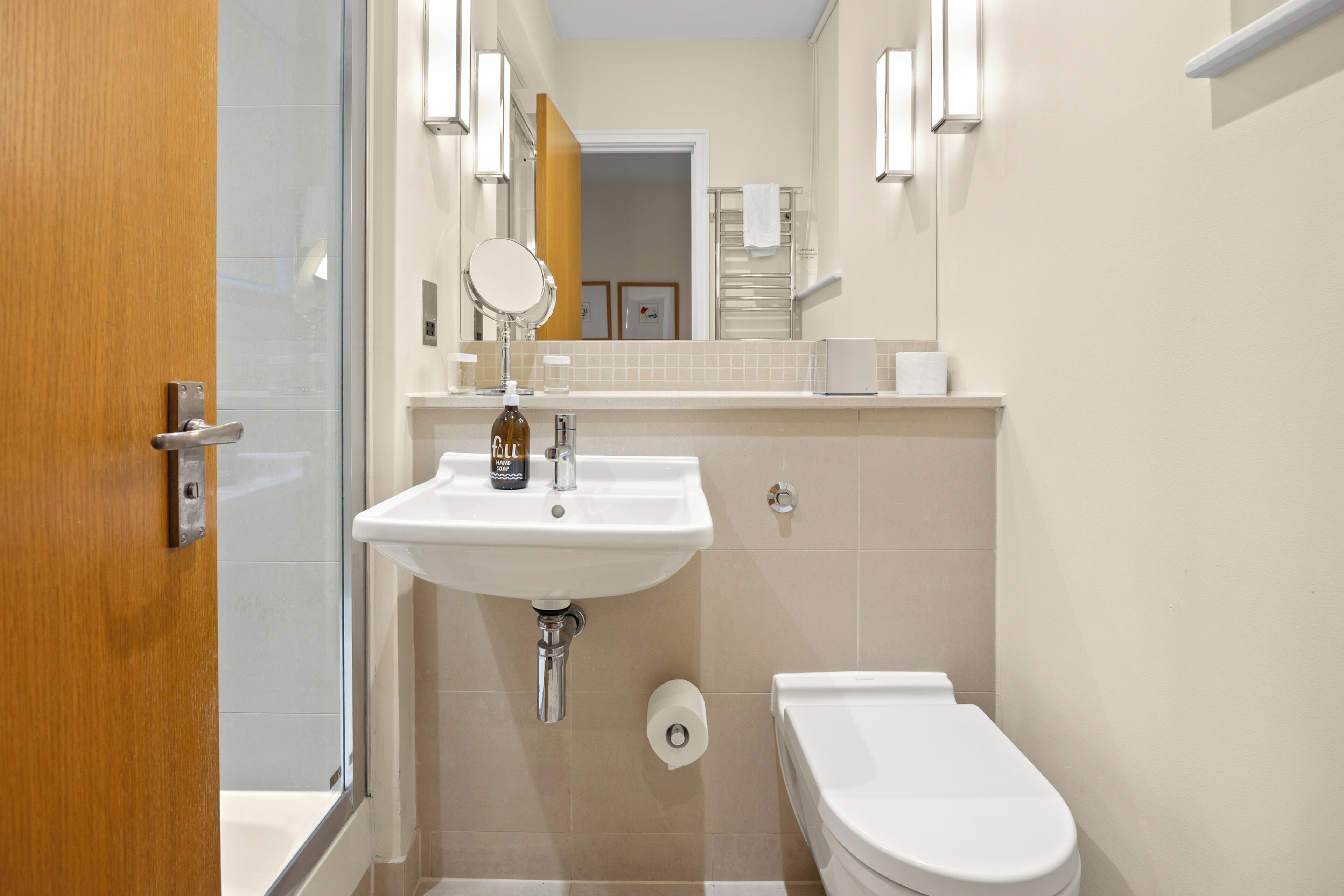 A bathroom with a white sink, mirror, and toilet.