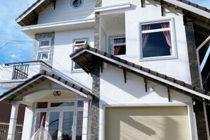 A multi-story building with a garage, a balcony, and a small porch area. - Tuong Vy Villa (Dalat)