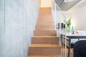 A staircase with wooden steps and white railings, leading to a room with a table and a plant. - LEGALAND Sangenjaya ANNEX (Tokyo)