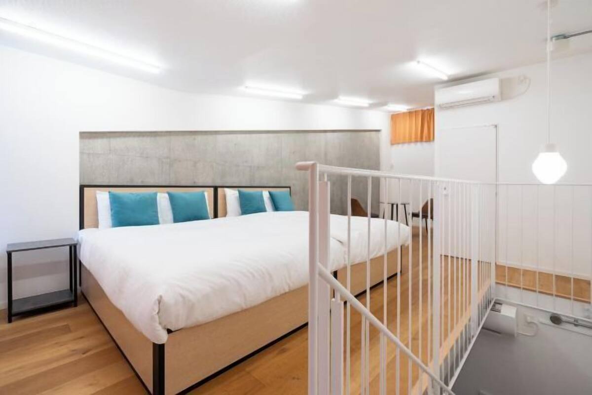 A modern bedroom with a bed, white railings, and a wooden floor.