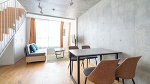 A modern interior with a dining table, chairs, a sofa, and a staircase. - LEGALAND Sangenjaya ANNEX (Tokyo)