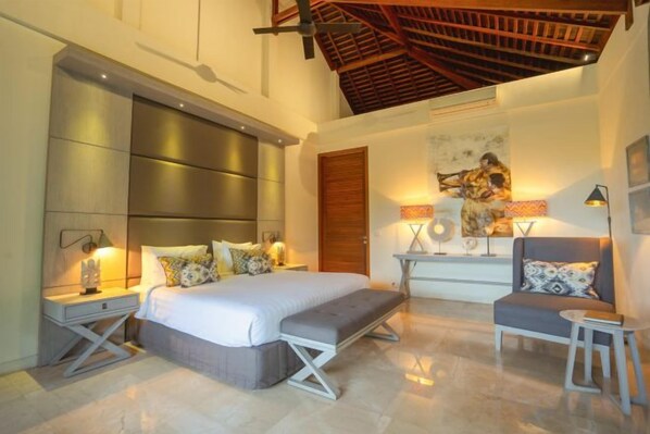 A modern bedroom with a large bed, bedside tables, a sofa, and a ceiling with exposed beams. - OMEKAI Cemagi by Nakula (Bali)