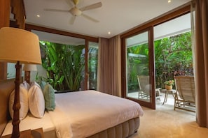 A bedroom with a bed, a ceiling fan, and a view of a garden through large glass doors. - OMEKAI Cemagi by Nakula (Bali)