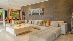 A modern living room with a sectional sofa, a coffee table, and a dining area in the background. - OMEKAI Cemagi by Nakula (Bali)