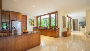 A modern kitchen with wooden cabinets, a stainless steel refrigerator, and a large window. - OMEKAI Cemagi by Nakula (Bali)