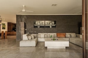 A modern living room with a sectional sofa, a coffee table, and a large painting on the wall. - OMEKAI Cemagi by Nakula (Bali)